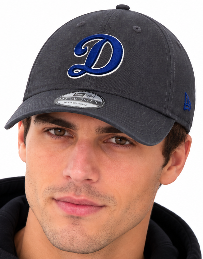 A man and a woman wearing matching dark gray baseball caps with a blue and white stylized letter 'D' logo on the front, photographed against a plain white background.