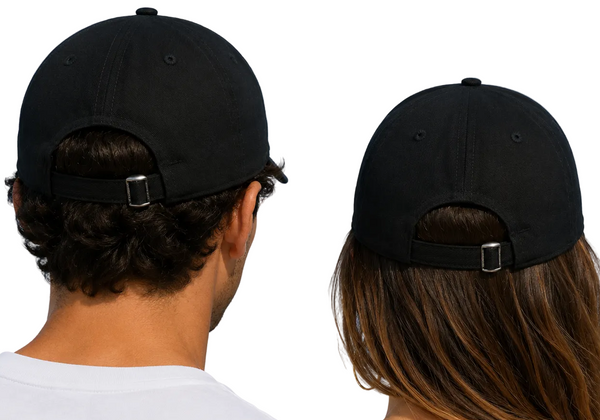 Two people seen from behind wearing black baseball caps with adjustable straps, set against a bright blue sky with light clouds.