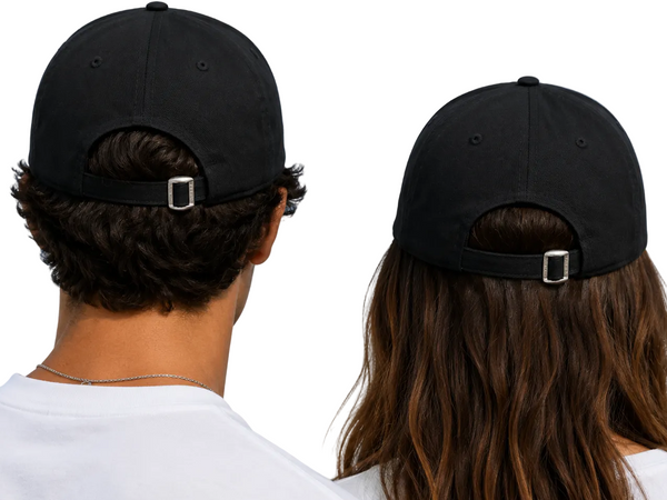 Two people shown from behind wearing black baseball caps with adjustable back straps and silver metal buckles, set against a clear blue sky.