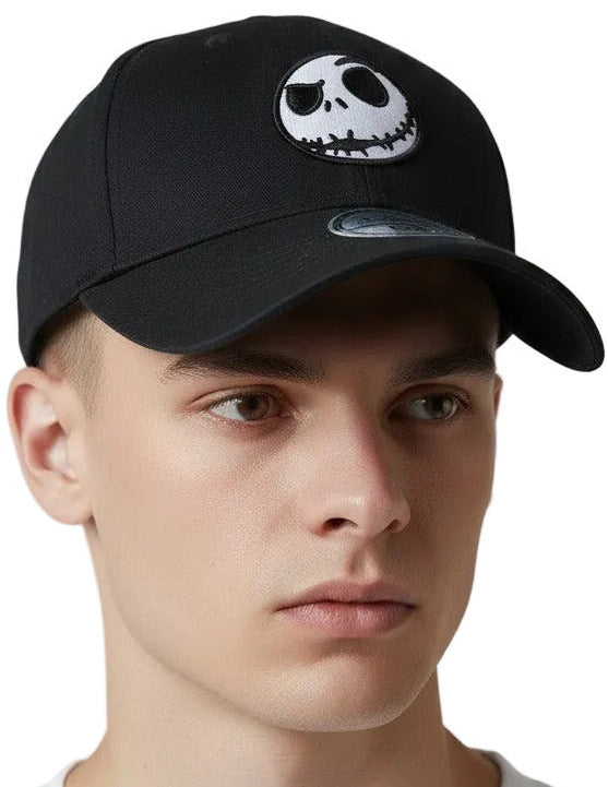A man wearing a black baseball cap with a white Jack Skellington graphic on the front, photographed against a light gray studio background.