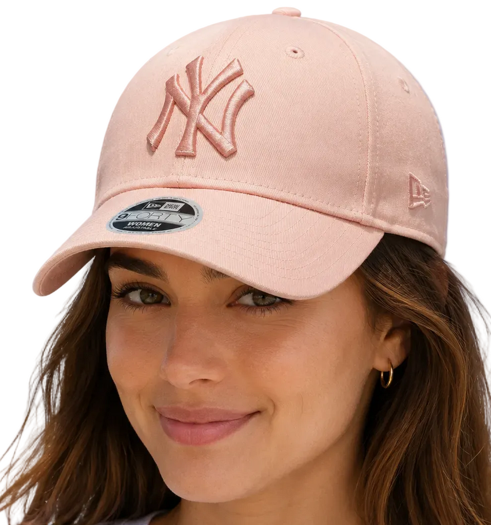 A woman wearing a light pink New York Yankees baseball cap with a matching embroidered 'NY' logo on the front and a New Era 9FORTY sticker on the brim, set against a plain white background.