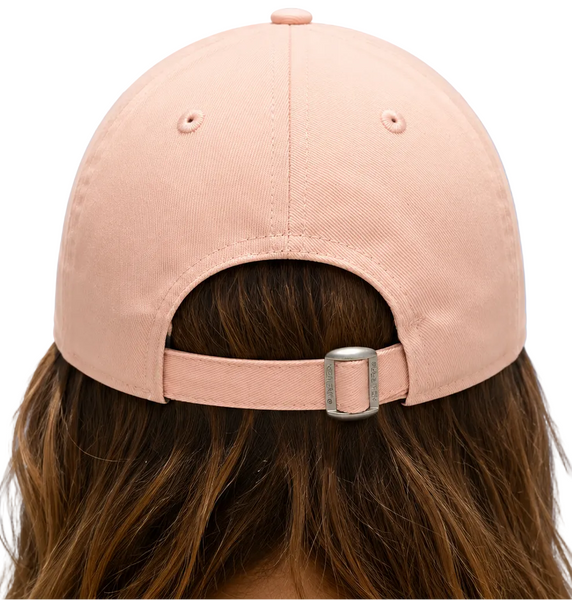 Back view of a dusty pink baseball cap with an adjustable strap and silver buckle, worn by a model with brown hair against a white background.
