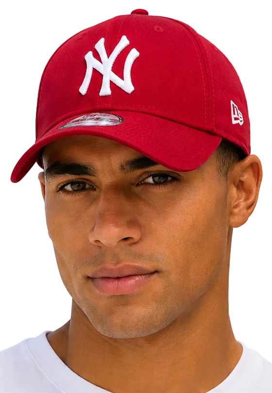 A close-up of a man wearing a red New York Yankees baseball cap with a white embroidered NY logo on the front and a white New Era flag on the side, set against a light blue sky background.